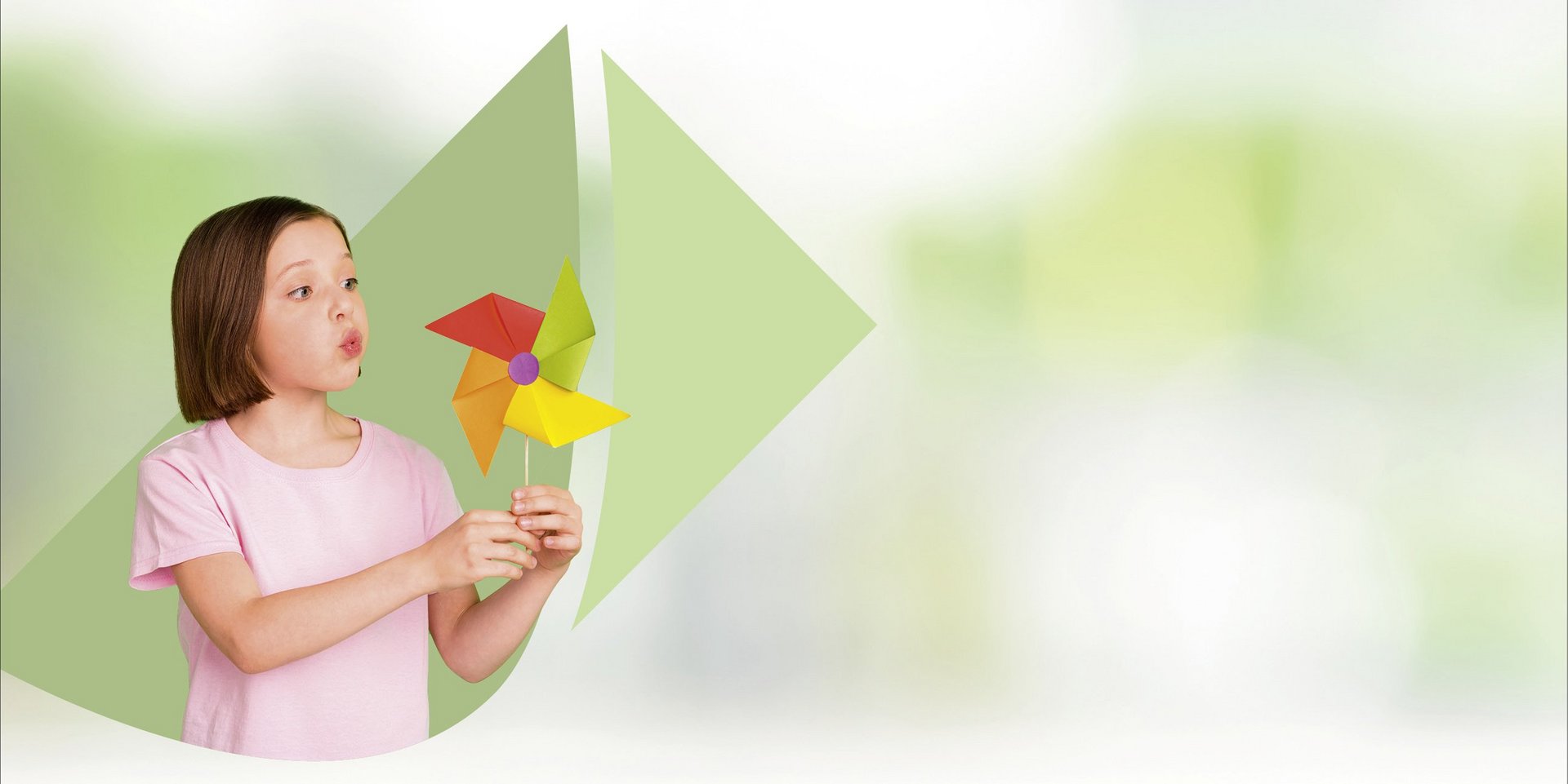 Ragazza che tiene in mano un piccolo mulino a vento e vi soffia sopra